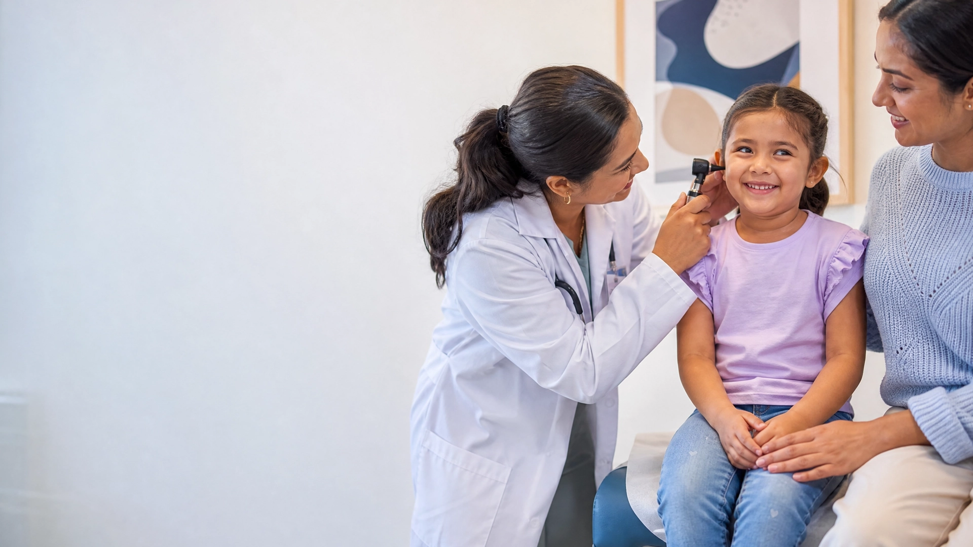 A mother and daughter smiling with their GP during a check-up